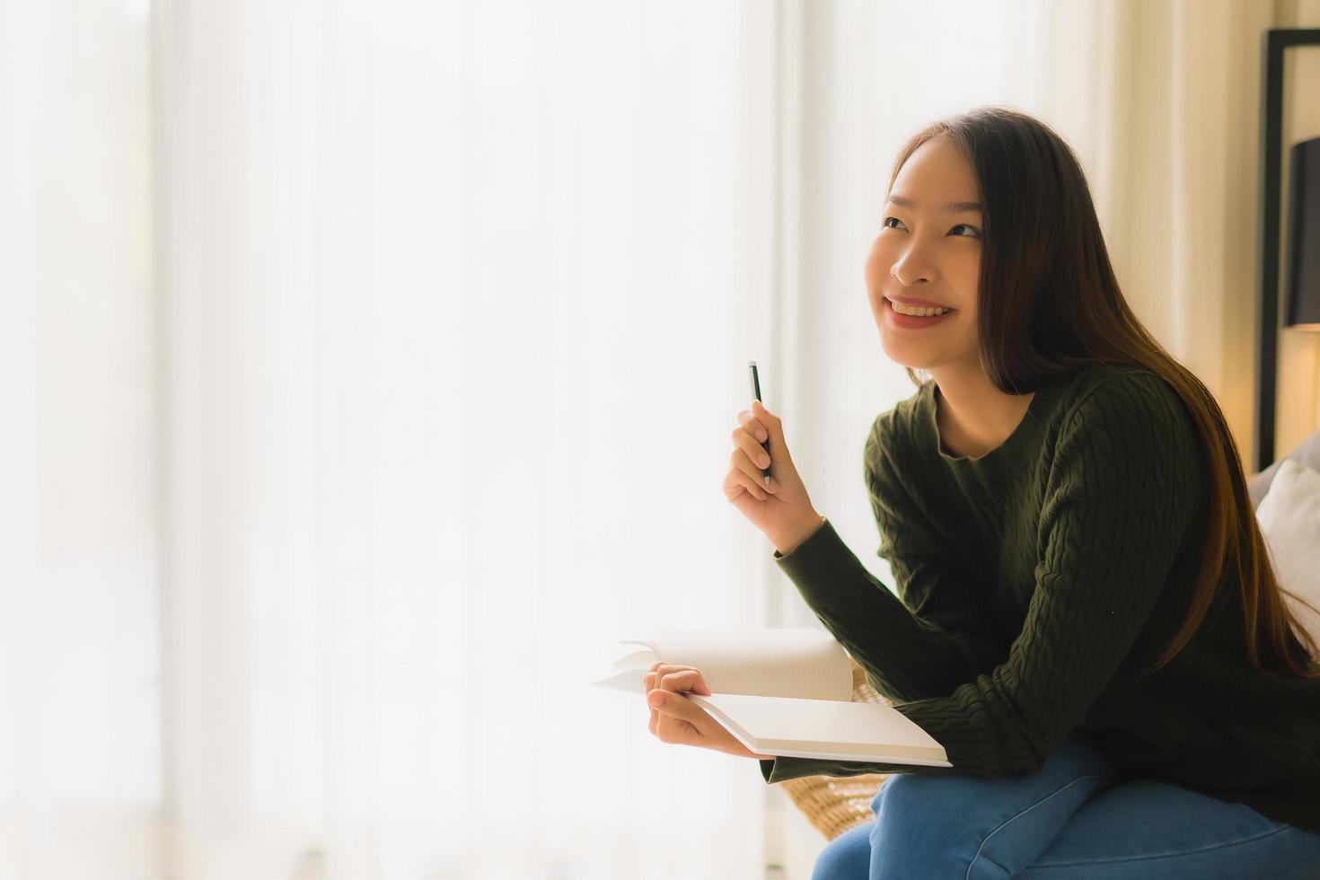 Portrait de belles jeunes femmes asiatiques lisant un livre et assis sur une chaise de canapé photo