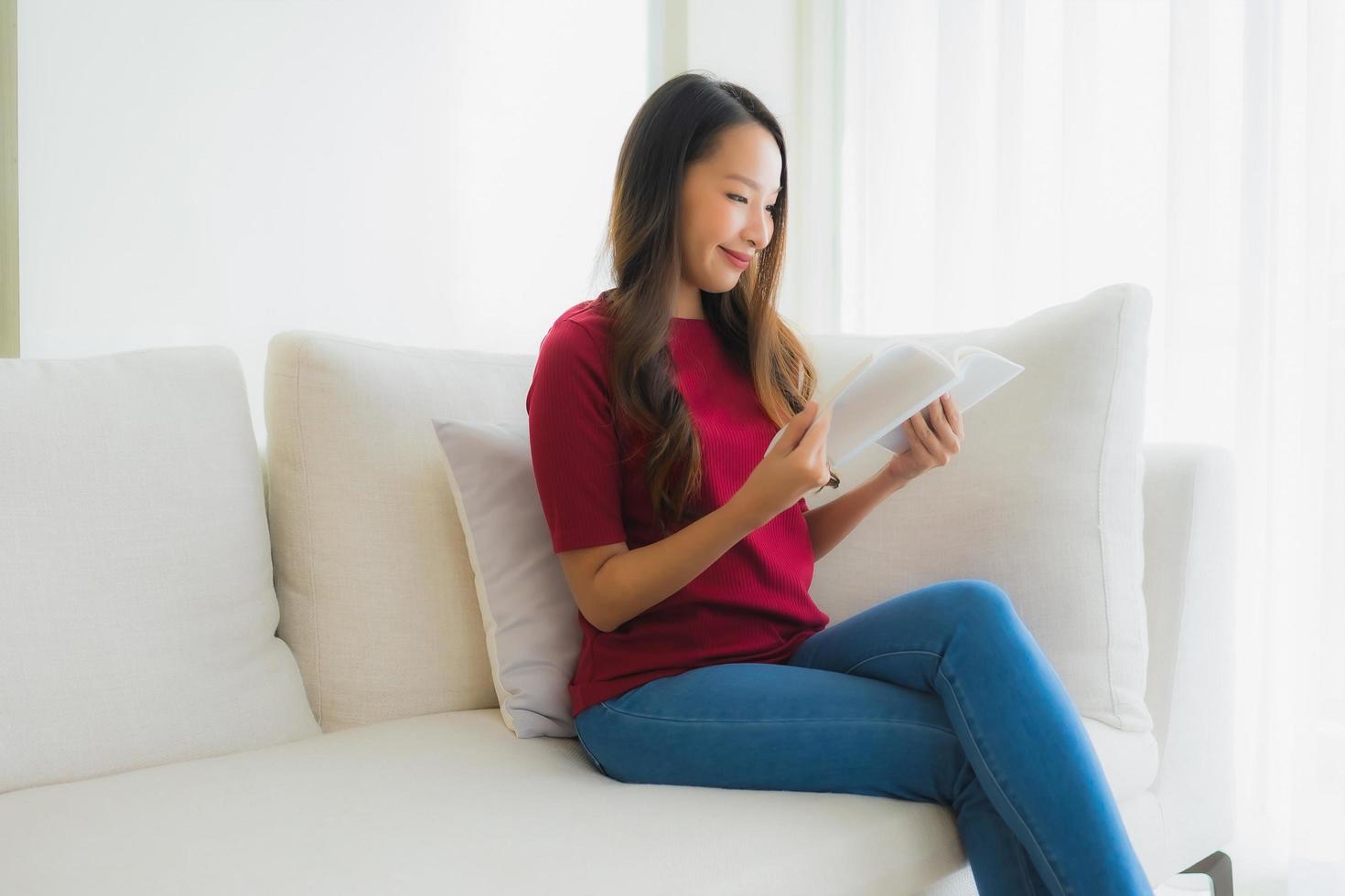 Portrait de belles jeunes femmes asiatiques lire un livre sur une chaise de canapé photo