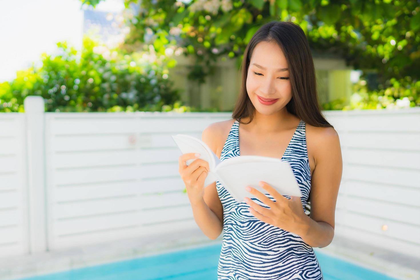 Portrait belle jeune femme asiatique sourire heureux avec livre de lecture autour de la piscine photo