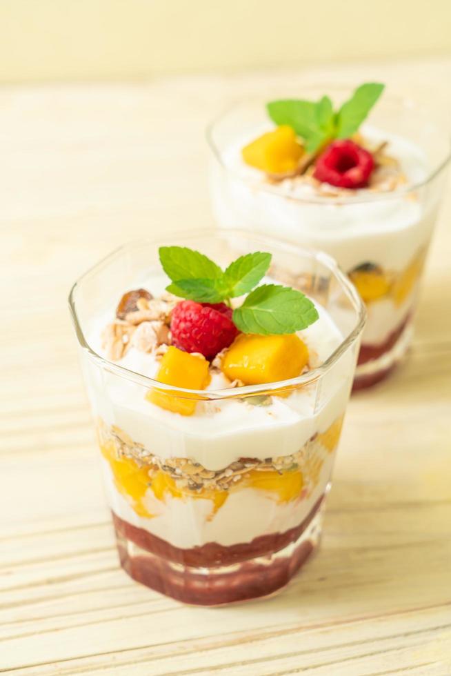 mangue fraîche faite maison et framboise fraîche avec yaourt et granola - style alimentaire sain photo