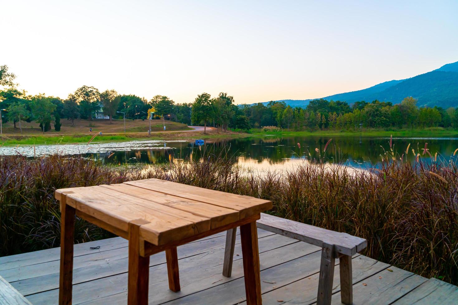 banc en bois avec un beau lac à chiang mai avec une montagne boisée et un ciel crépusculaire en thaïlande photo