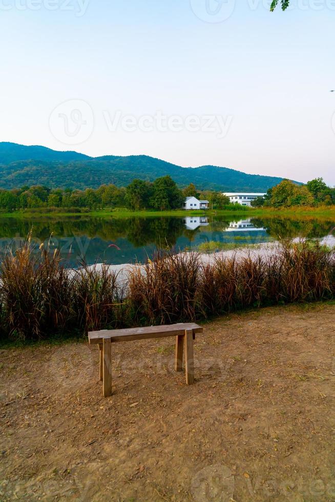 banc en bois avec un beau lac à chiang mai avec une montagne boisée et un ciel crépusculaire en thaïlande photo