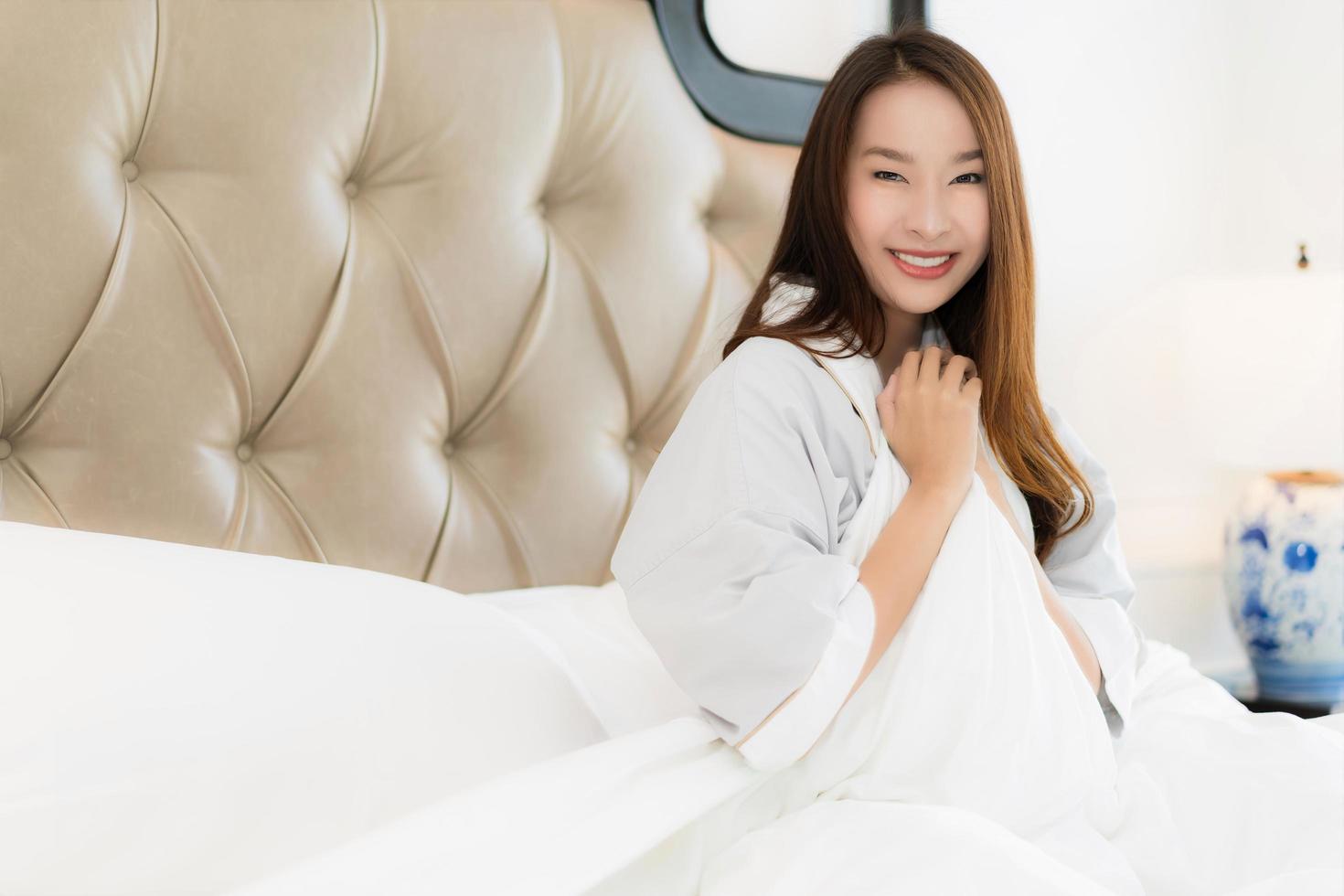 Portrait belle jeune femme asiatique se réveiller avec heureux et sourire sur le lit à l'intérieur de la chambre photo
