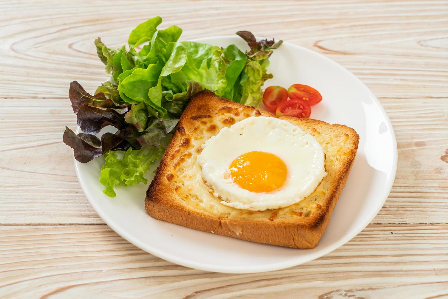 pain maison grillé avec du fromage et un œuf au plat sur le dessus avec une salade de légumes pour le petit-déjeuner photo