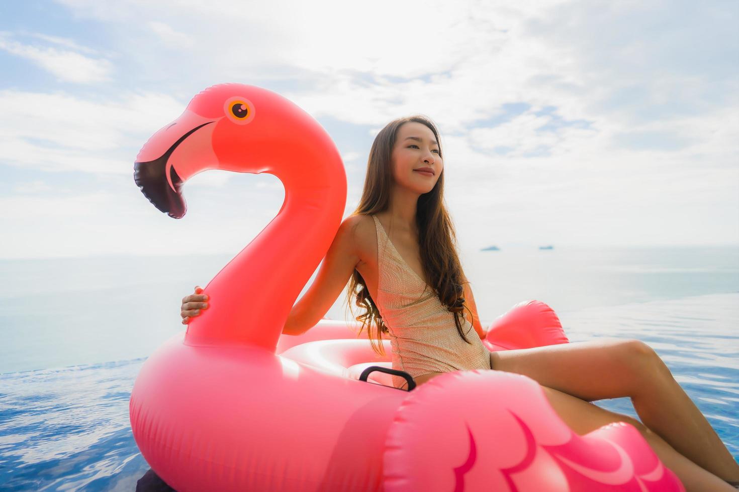 Portrait young asian woman on flamingo flotteur gonflable autour de la piscine extérieure de l'hôtel resort photo