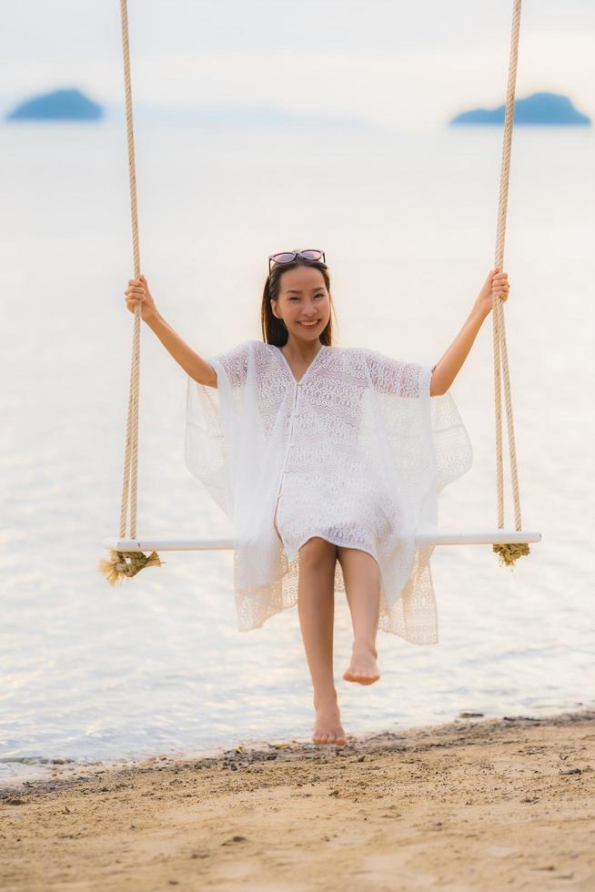 Portrait belle jeune femme asiatique assise sur la balançoire autour de la plage mer océan pour se détendre photo