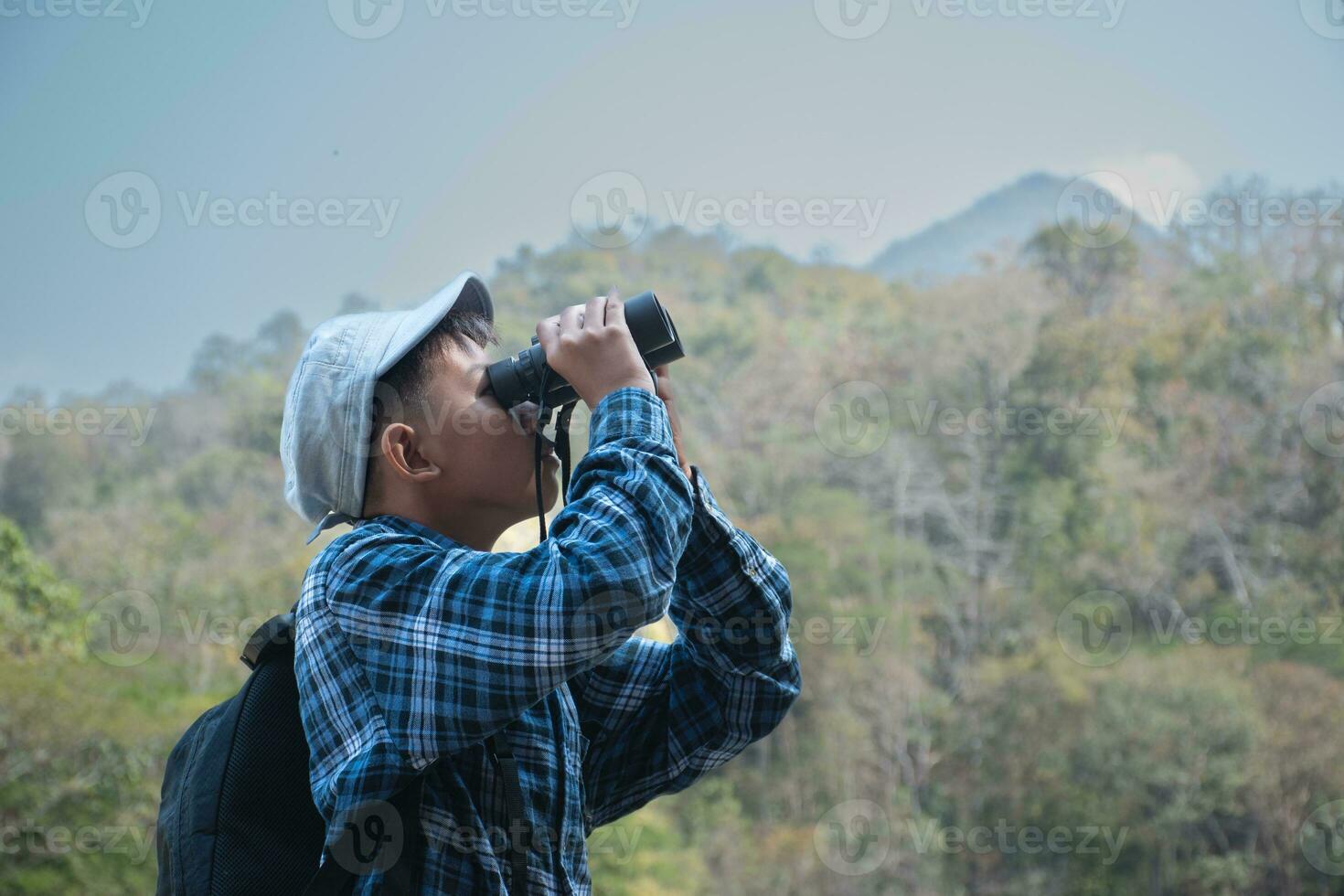 asiatique garçon dans plaid chemise et casquette Faire le été activité à local nationale parc par en train de regarder des oiseaux, poisson, insectes, animaux, des arbres, fleur par en utilisant carte et jumelles, doux et sélectif se concentrer. photo