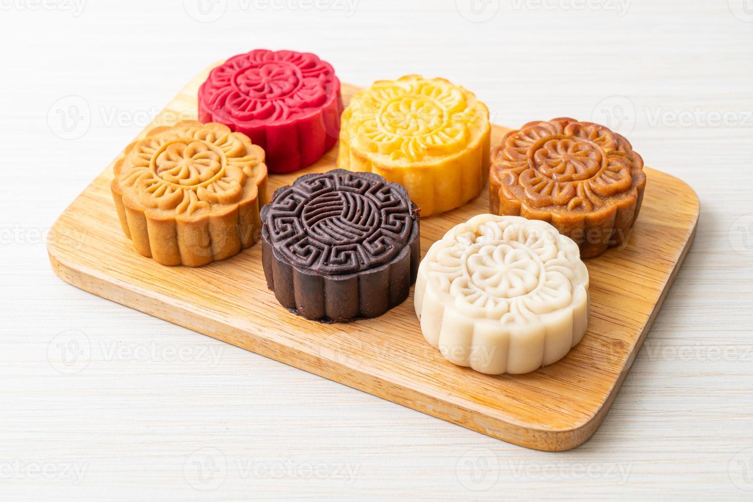 Gâteau de lune chinois coloré aux saveurs mélangées sur plaque de bois photo