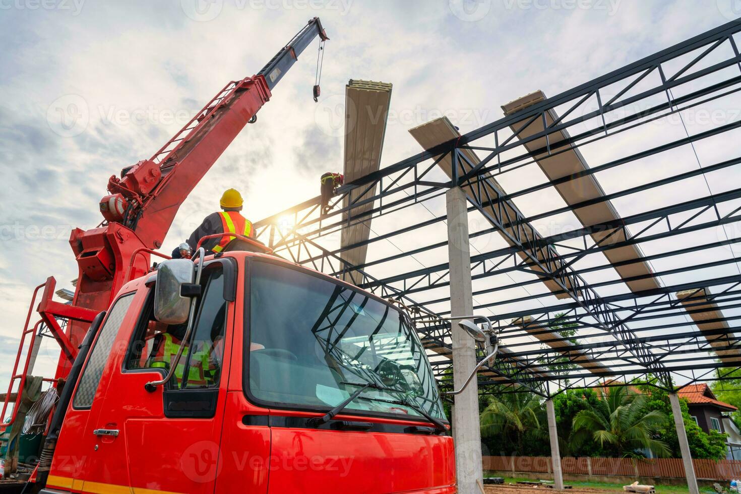 une grue chauffeur est pilotage une grue à ascenseur une toit ou pu mousse toit feuille sur une acier toit structure à une construction placer. installer une Nouveau toit. photo