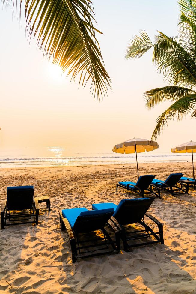 chaise de plage parapluie avec palmier et plage de la mer au lever du soleil - concept de vacances et de vacances photo
