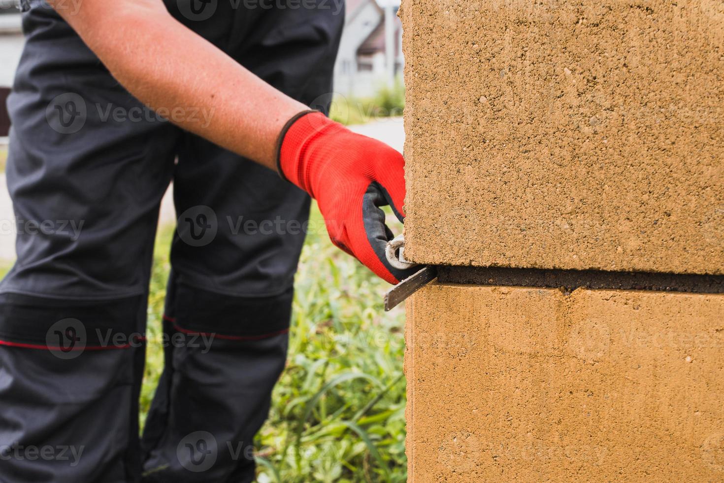 colle à base de ciment pour bloc de pierre de maçonnerie et brique dans la construction - un maçon professionnel au travail photo