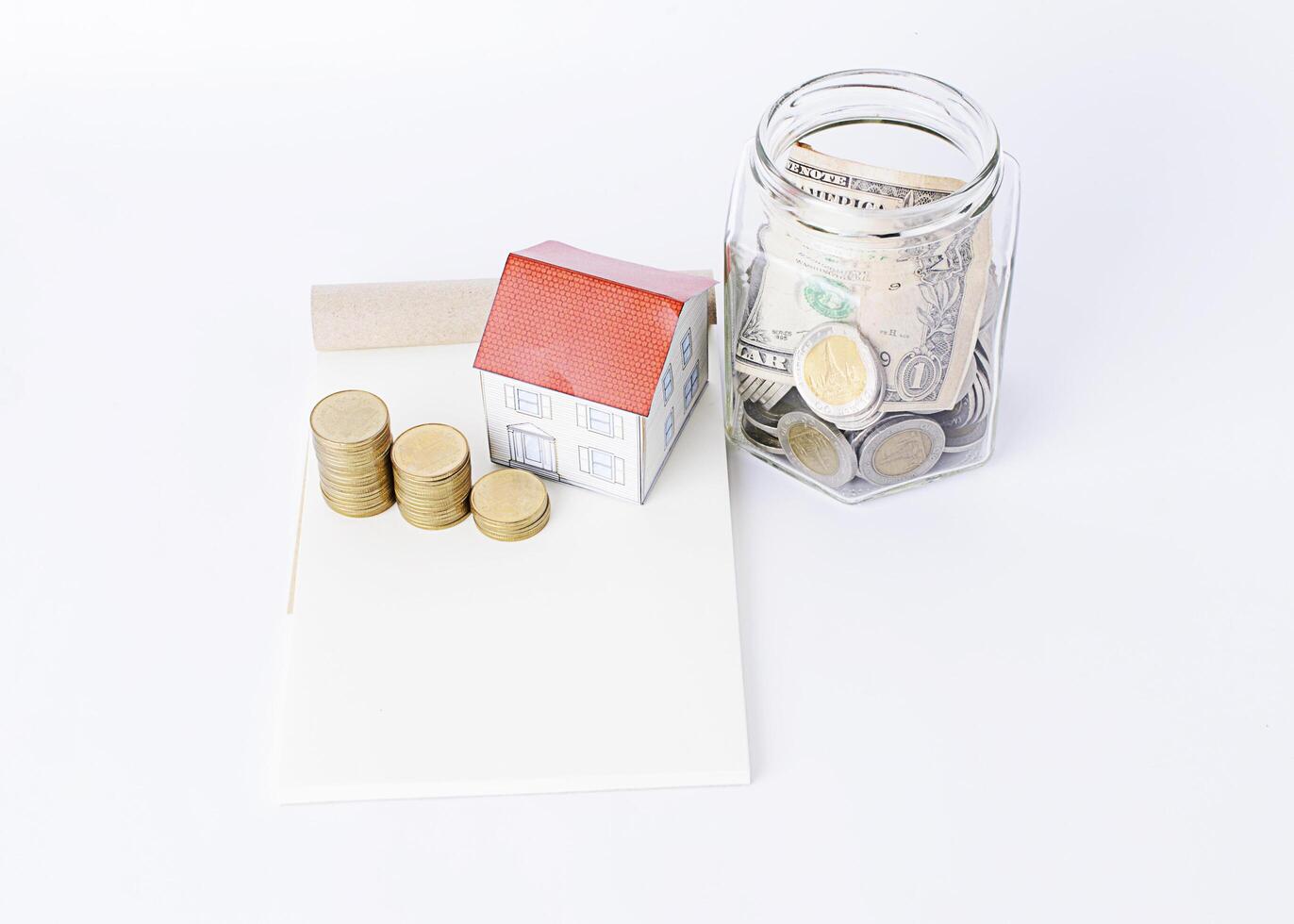 économiser de l'argent avec des bouteilles en verre et une maison en papier et une pile de pièces dessus photo