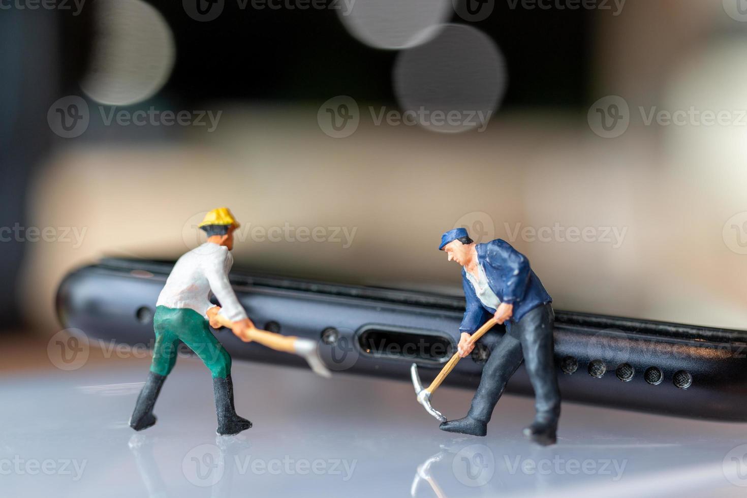 travailleur miniature avec des outils réparant un téléphone portable photo