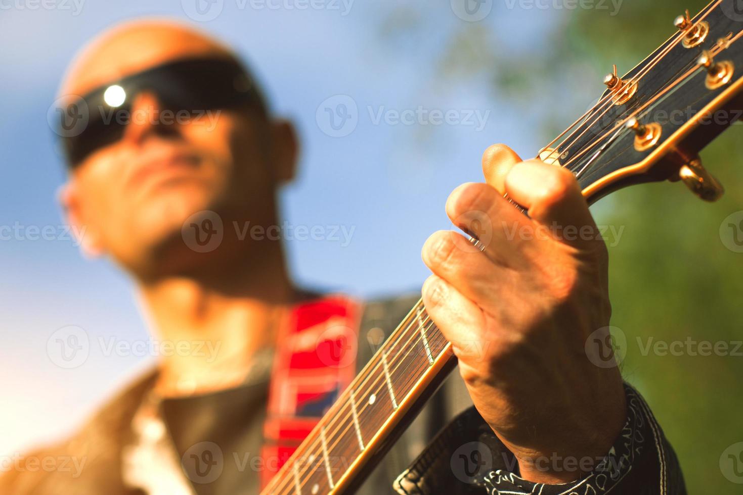 manche de guitare acoustique avec arrangement à la main avec le guitariste flou photo