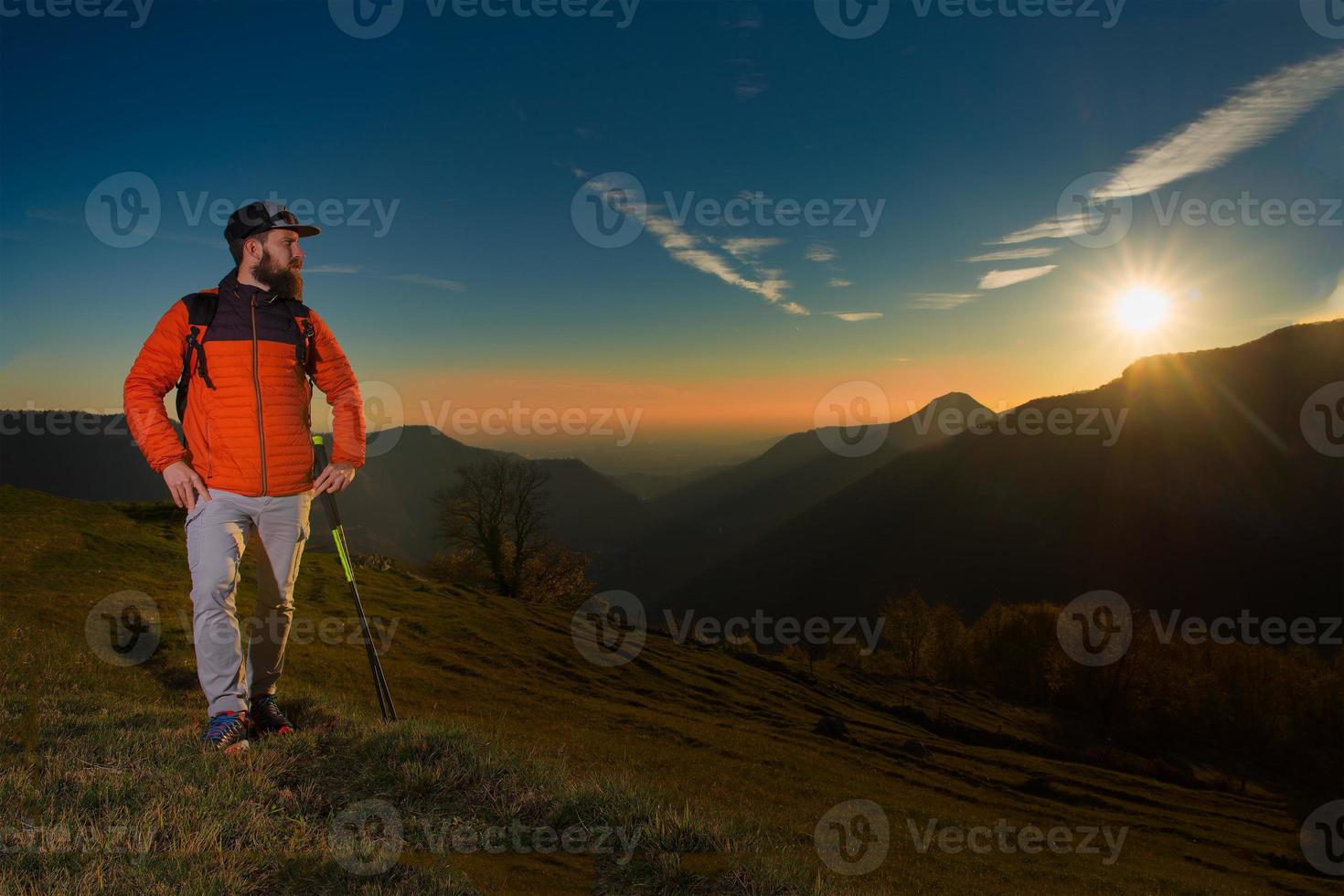 jeune homme à la barbe regardant le panorama se repose pendant un trek de marche nordique photo