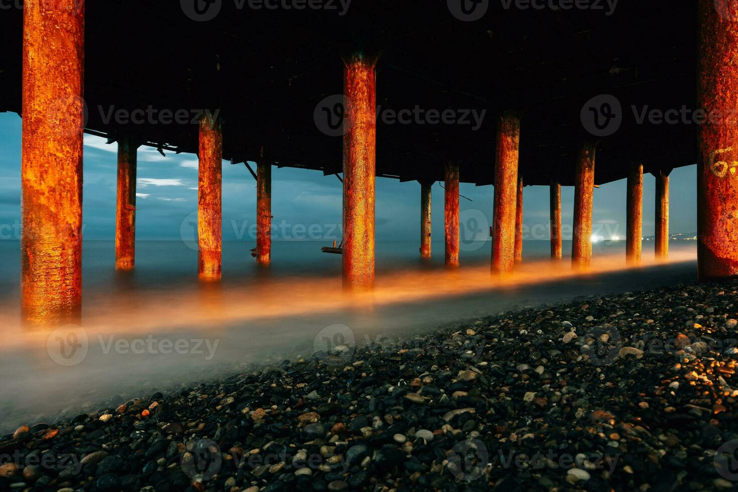 vagues mousse en dessous de le pont, le fer Colonnes à le rivage. photo de vagues sur une longue exposition. soir photo de le mer et Colonnes avec rouille