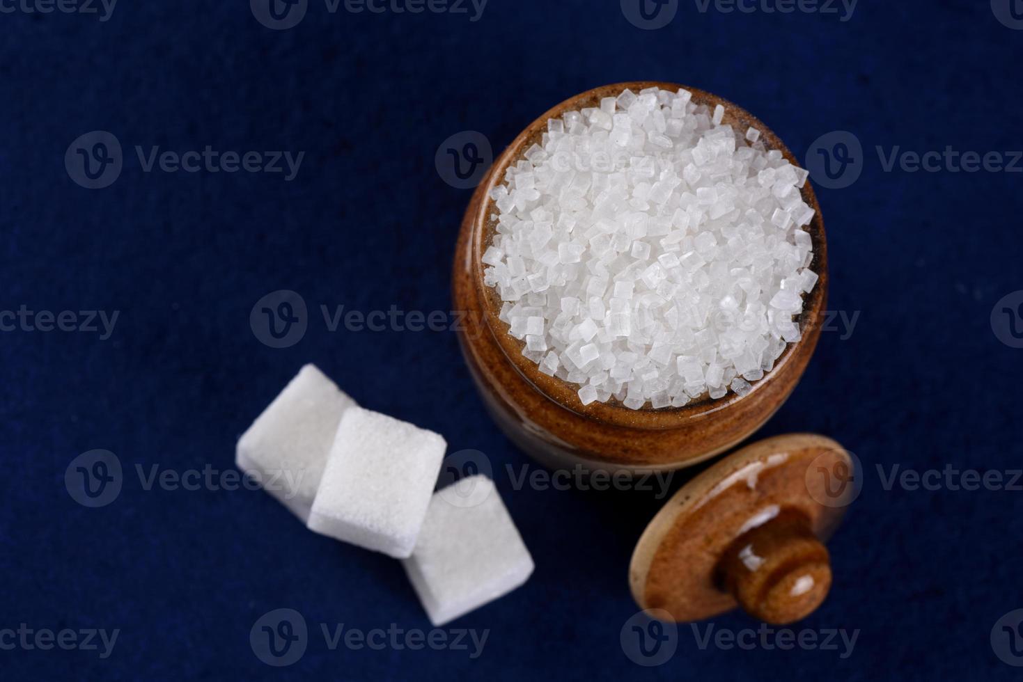 du sucre. sucre cristallisé blanc et sucre raffiné sur fond bleu photo