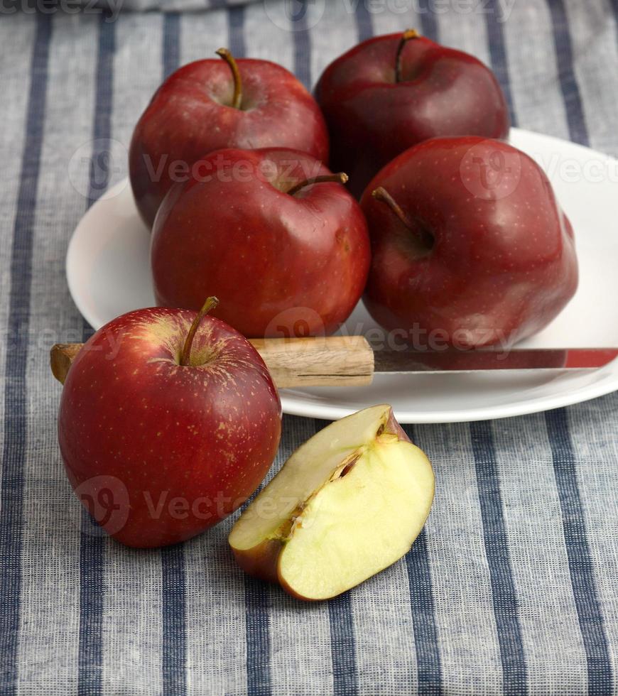 De délicieuses pommes dans une assiette avec un couteau sur une nappe à rayures photo