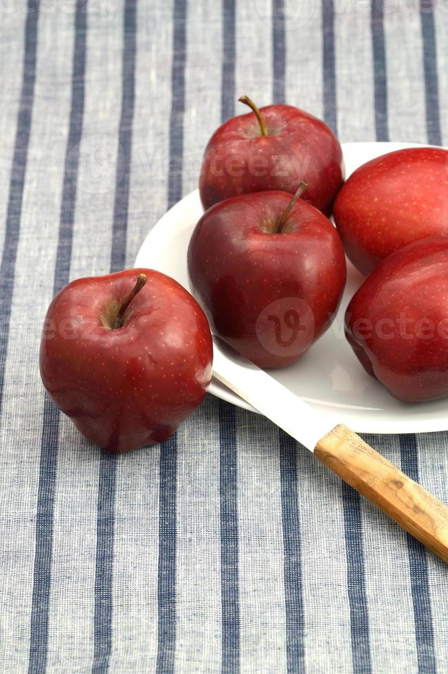 De délicieuses pommes dans une assiette avec un couteau sur une nappe à rayures photo