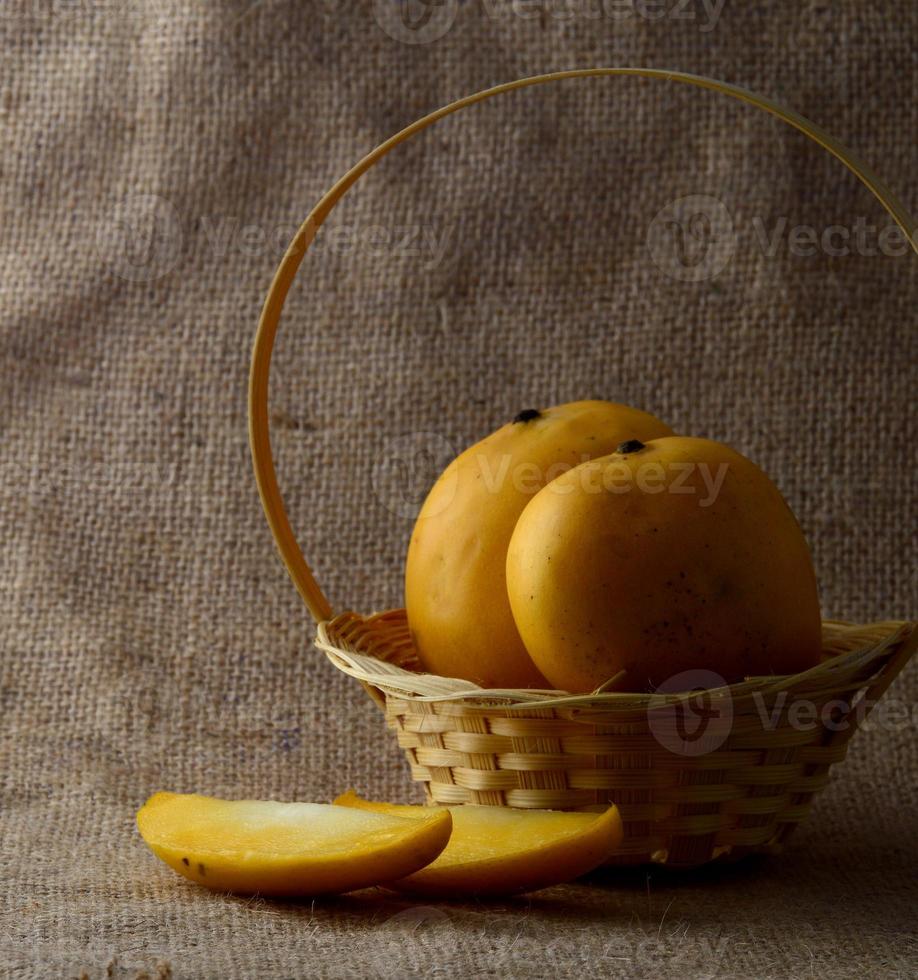 Fruits de mangue dans le panier sur fond de tissu de sac photo