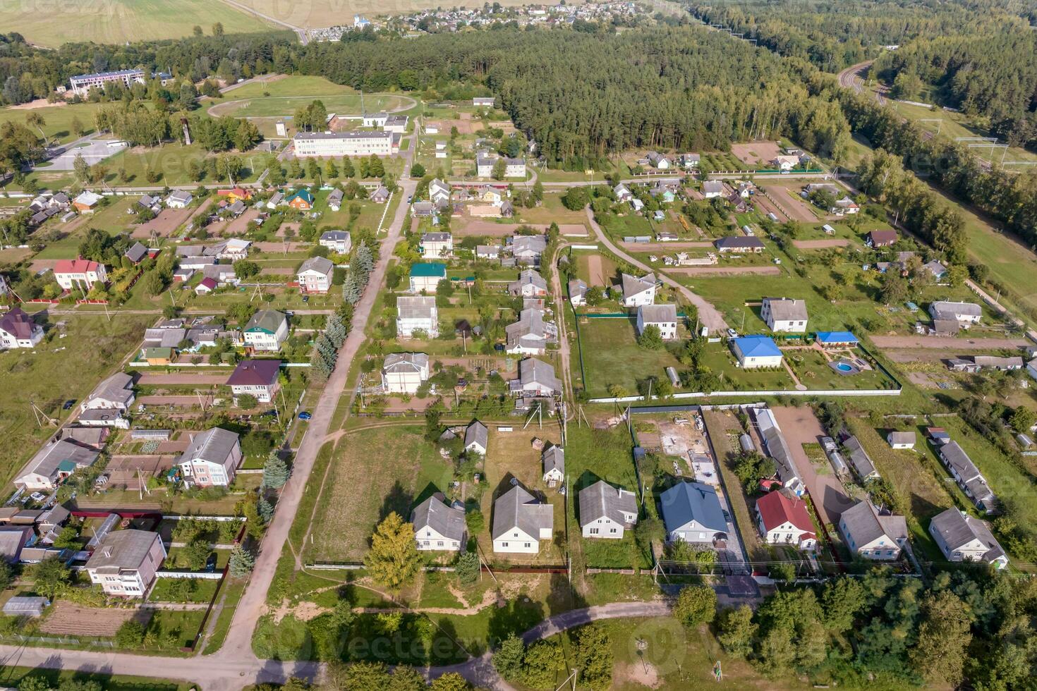 panoramique aérien vue de éco village avec en bois Maisons, gravier route, jardins et vergers photo