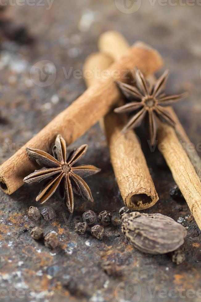 bâtons de cannelle, étoiles d'anis, cardamome et grains de poivre noir sur fond texturé photo