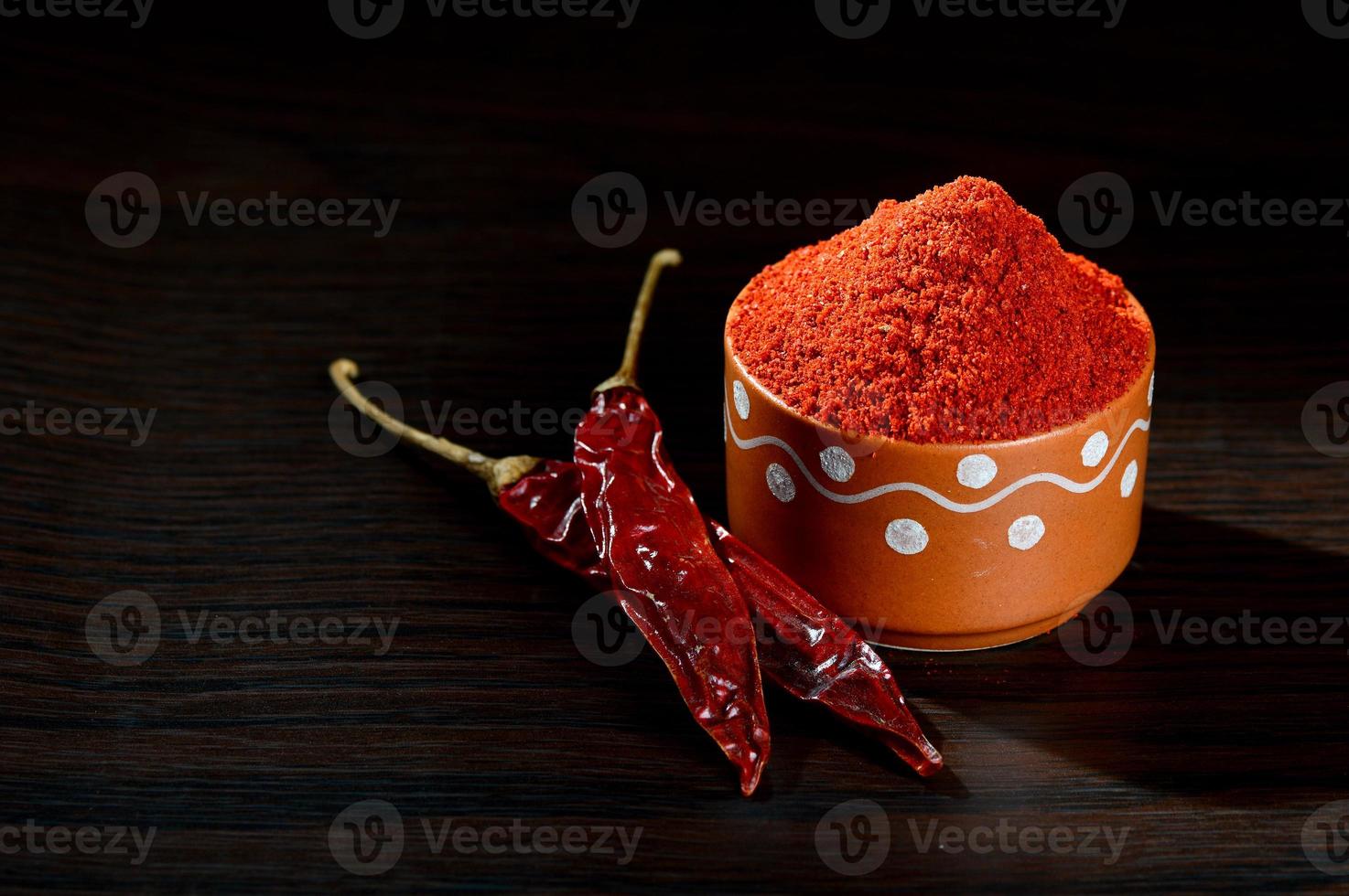 poudre froide dans un pot en argile avec des piments rouges frais et séchés sur fond de bois photo