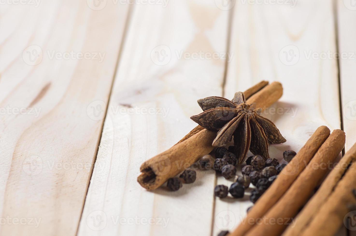 épices et herbes. ingrédients de la nourriture et de la cuisine. bâtons de cannelle, étoiles d'anis et grains de poivre noir sur fond de bois. photo