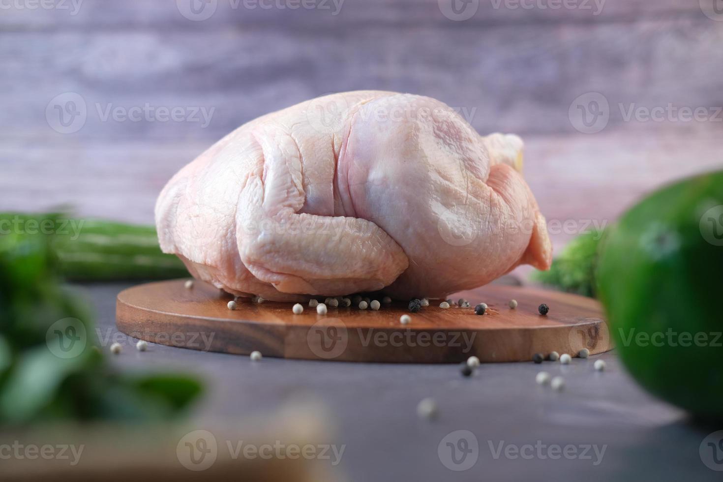 poulet entier cru avec des légumes sur fond de bois photo