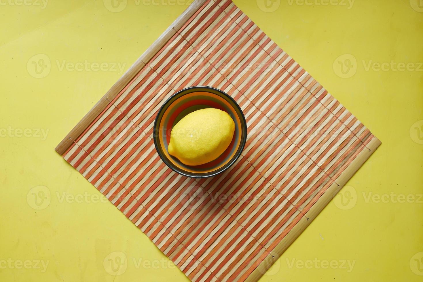 citron jaune dans un bol sur fond jaune avec espace de copie. photo