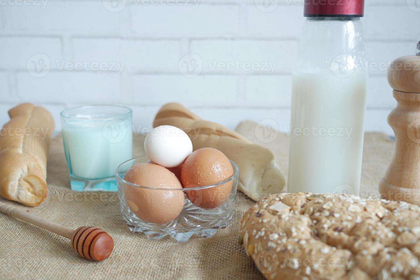 oeufs dans un bol, pain complet et lait sur table photo