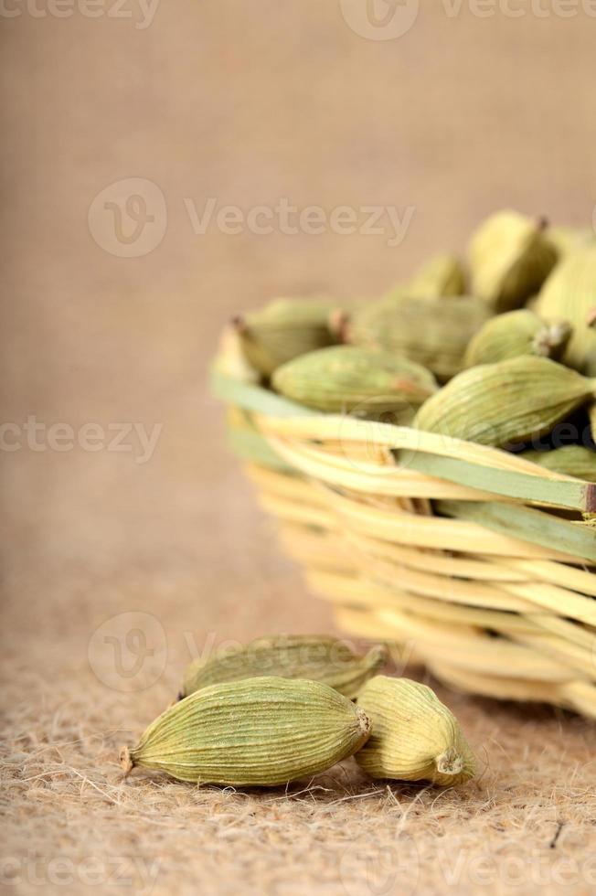 Gousses de cardamome verte dans un panier en bambou sur un sac en tissu photo