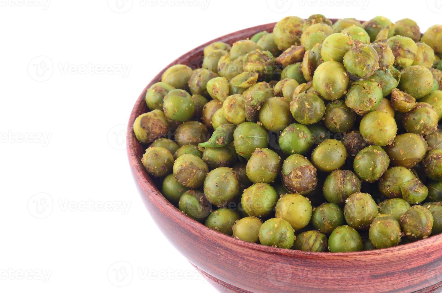 collation indienne de pois verts frits épicés. pois verts salés séchés dans un bol en bois avec cuillère sur fond blanc photo