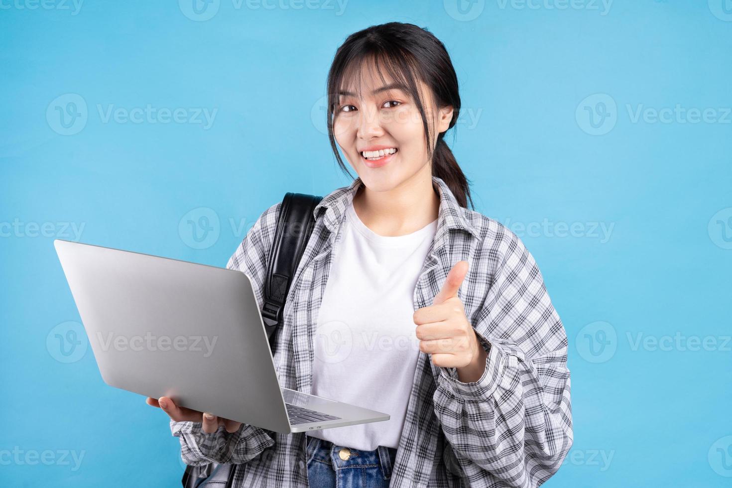 étudiante asiatique avec une expression ludique sur fond bleu photo