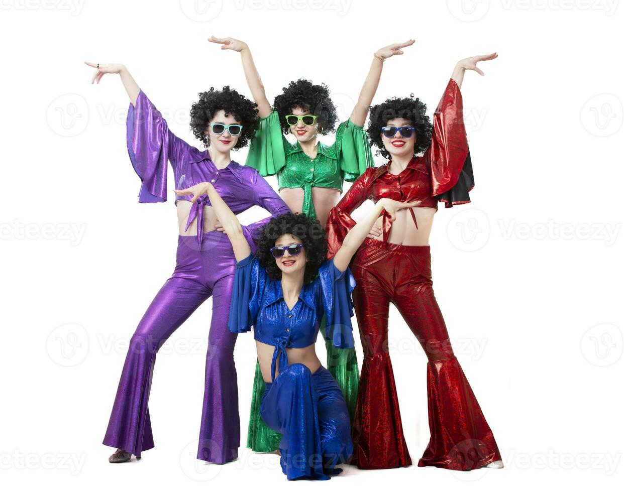 une groupe de les filles dans coloré évasé costume et afro perruques pose contre une blanc Contexte. disco style de le 80 ou années soixante-dix. photo