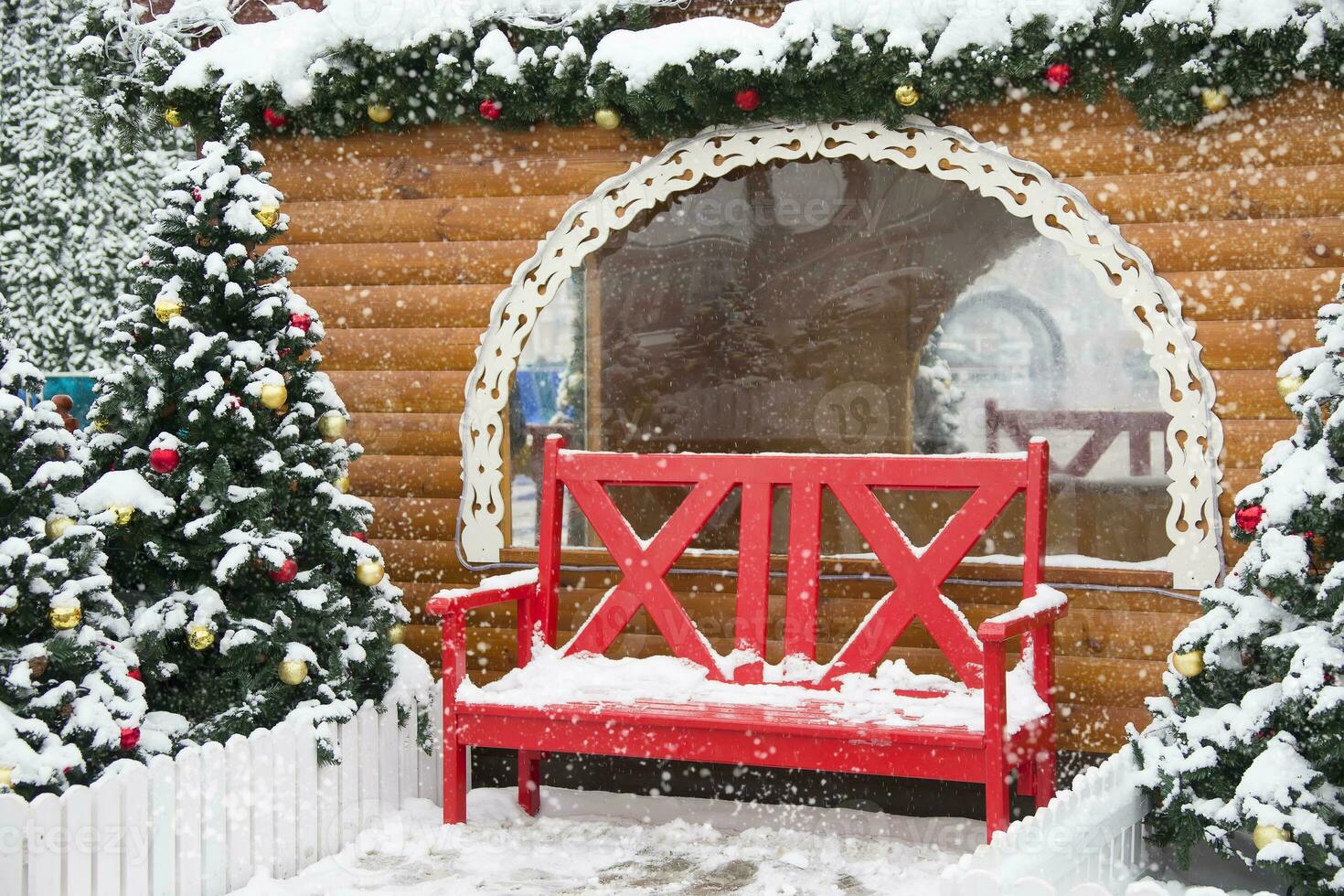 Nouveau années paysage. rouge banc sur le Contexte de des arbres et une en bois cabane. paysage pour le Nouveau année.en bois maison banc Noël arbre photo