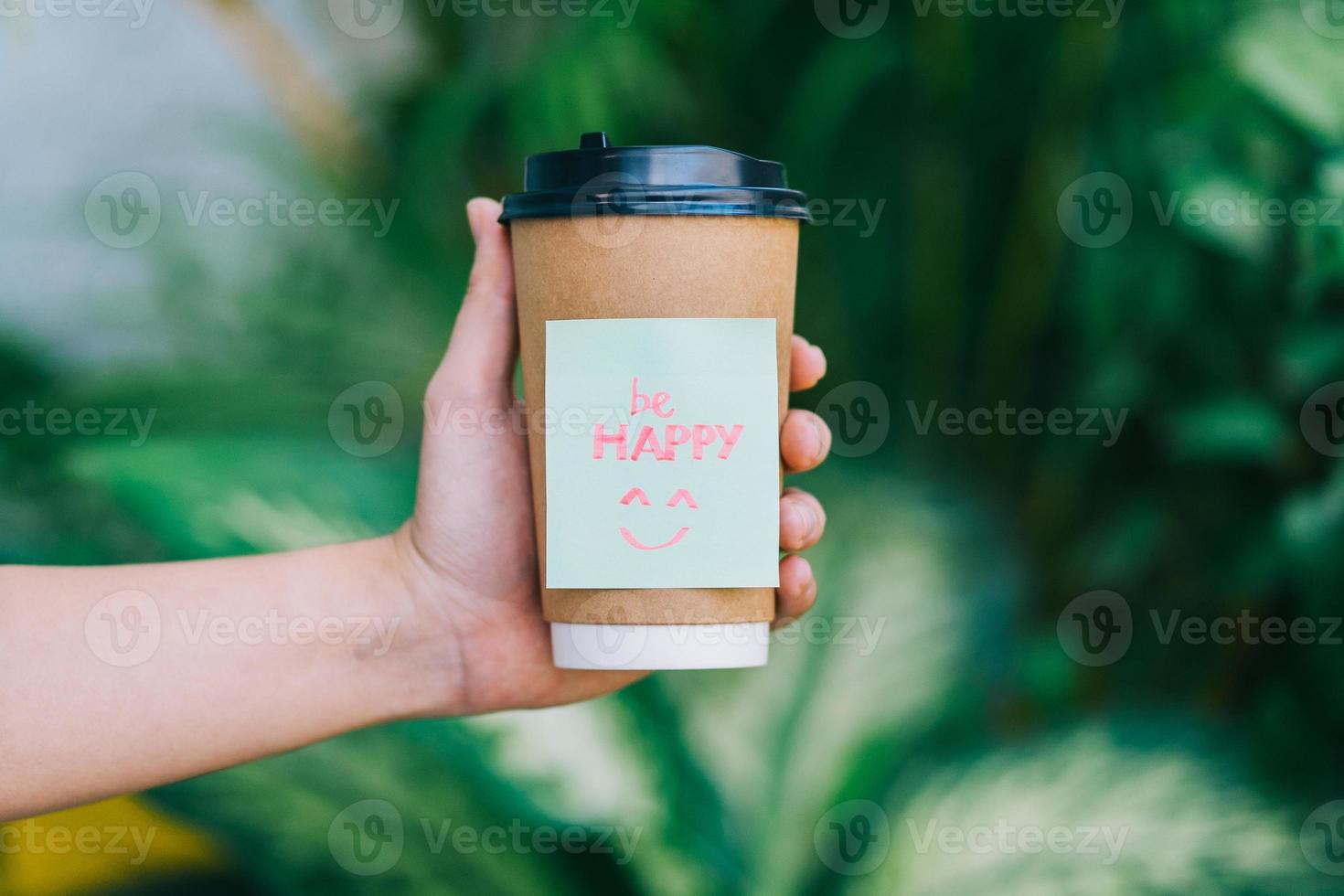 une main tenant une tasse de café avec le mot être heureux avec un fond vert photo