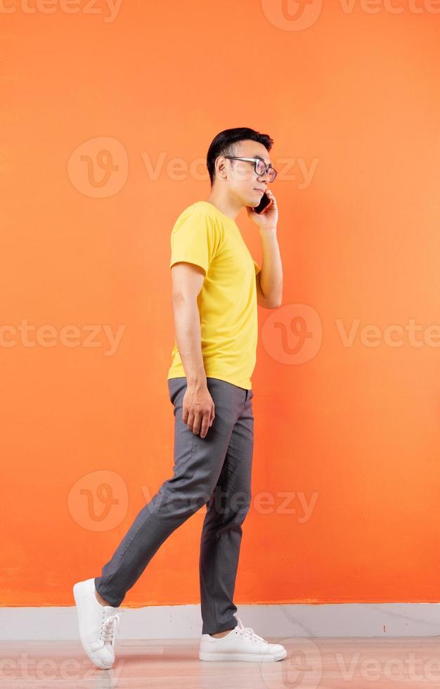 photo du corps entier d'un homme asiatique en chemise jaune sur fond orange