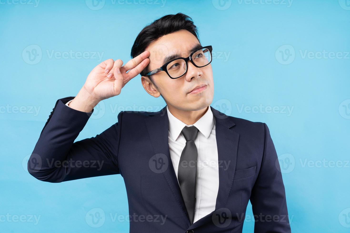 homme d'affaires asiatique pensant au travail sur fond bleu photo