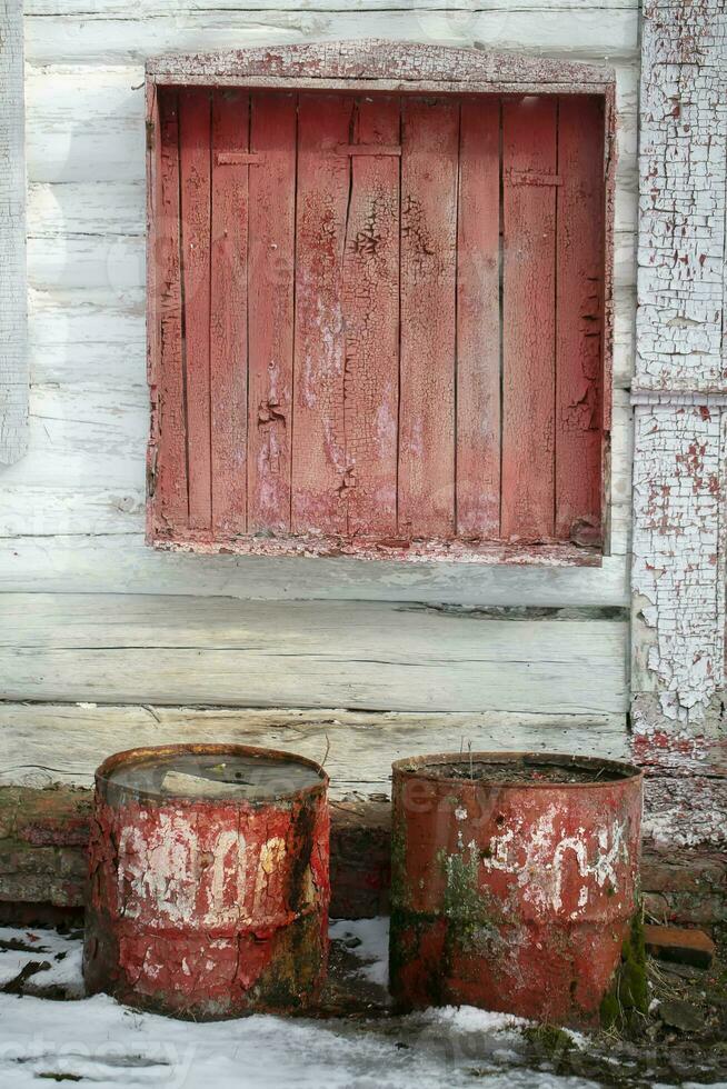 Contexte vieux et abandonné. en bois mur avec peeling peindre et rouillé barils. photo