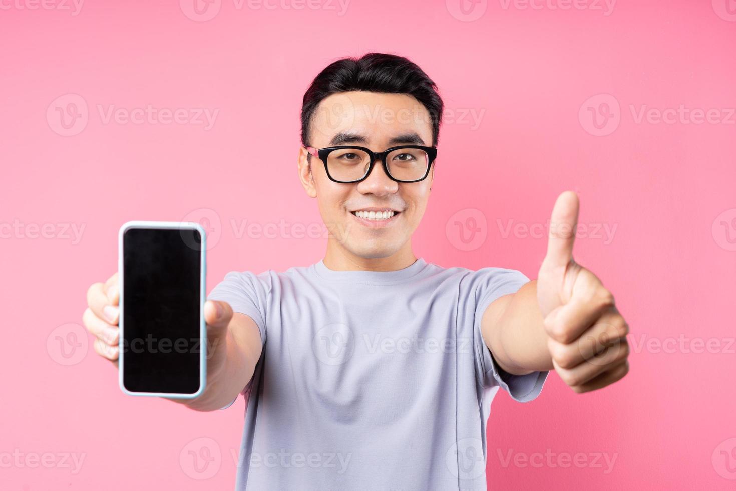 portrait d'un homme asiatique utilisant un smartphone sur fond rose photo