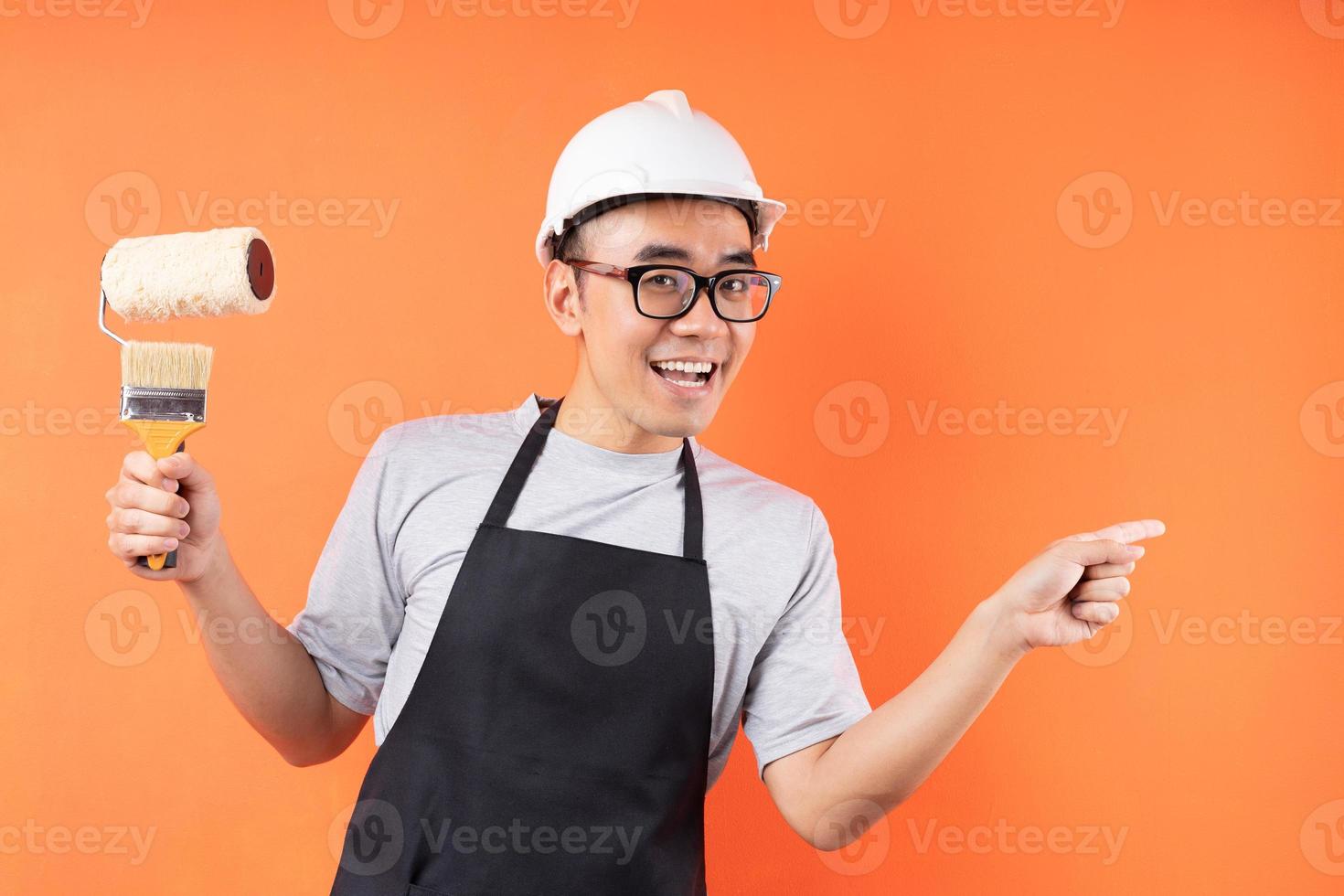 peintre asiatique tenant un pinceau posant sur fond orange photo