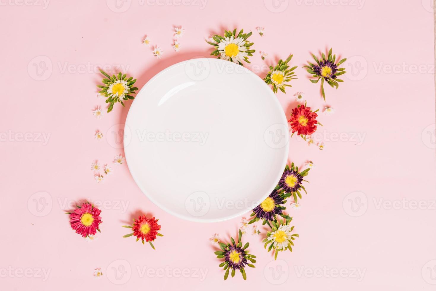 la plaque blanche ronde est placée sur un fond rose avec des fleurs autour photo
