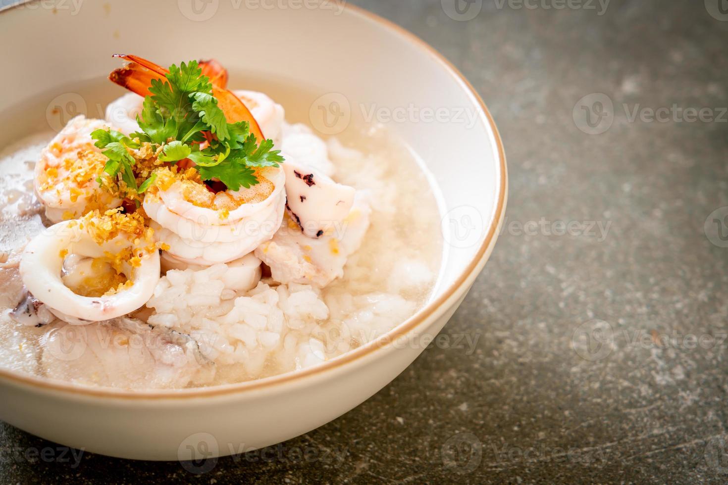 bouillie ou soupe de riz bouilli avec des fruits de mer de crevettes, de calmars et de poisson dans un bol photo