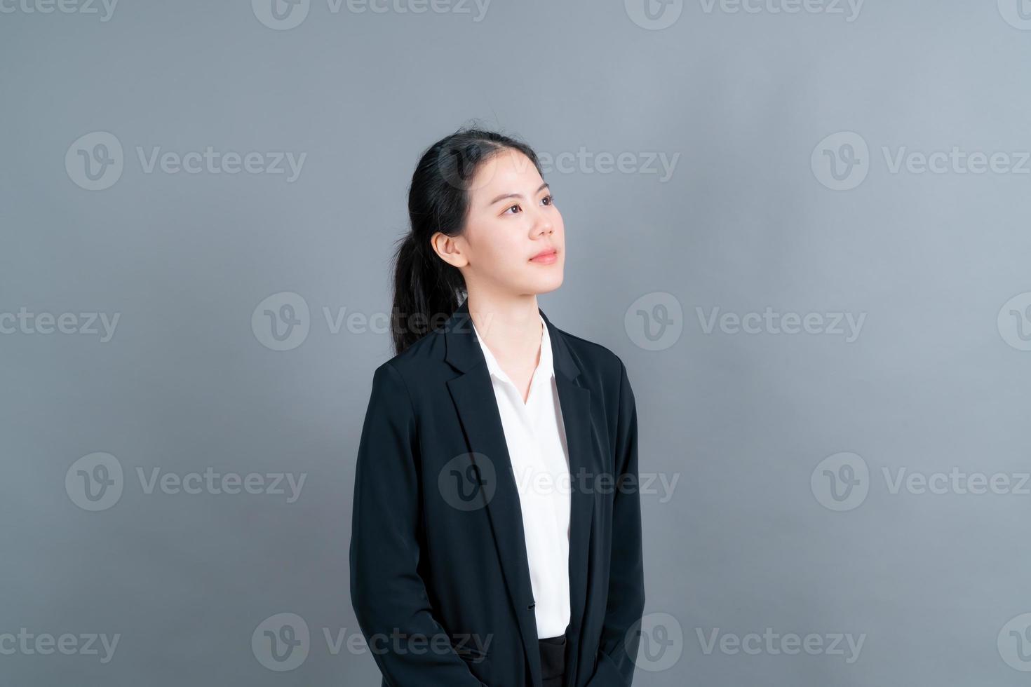 femme asiatique heureuse avec un visage heureux dans des vêtements de bureau sur fond gris photo