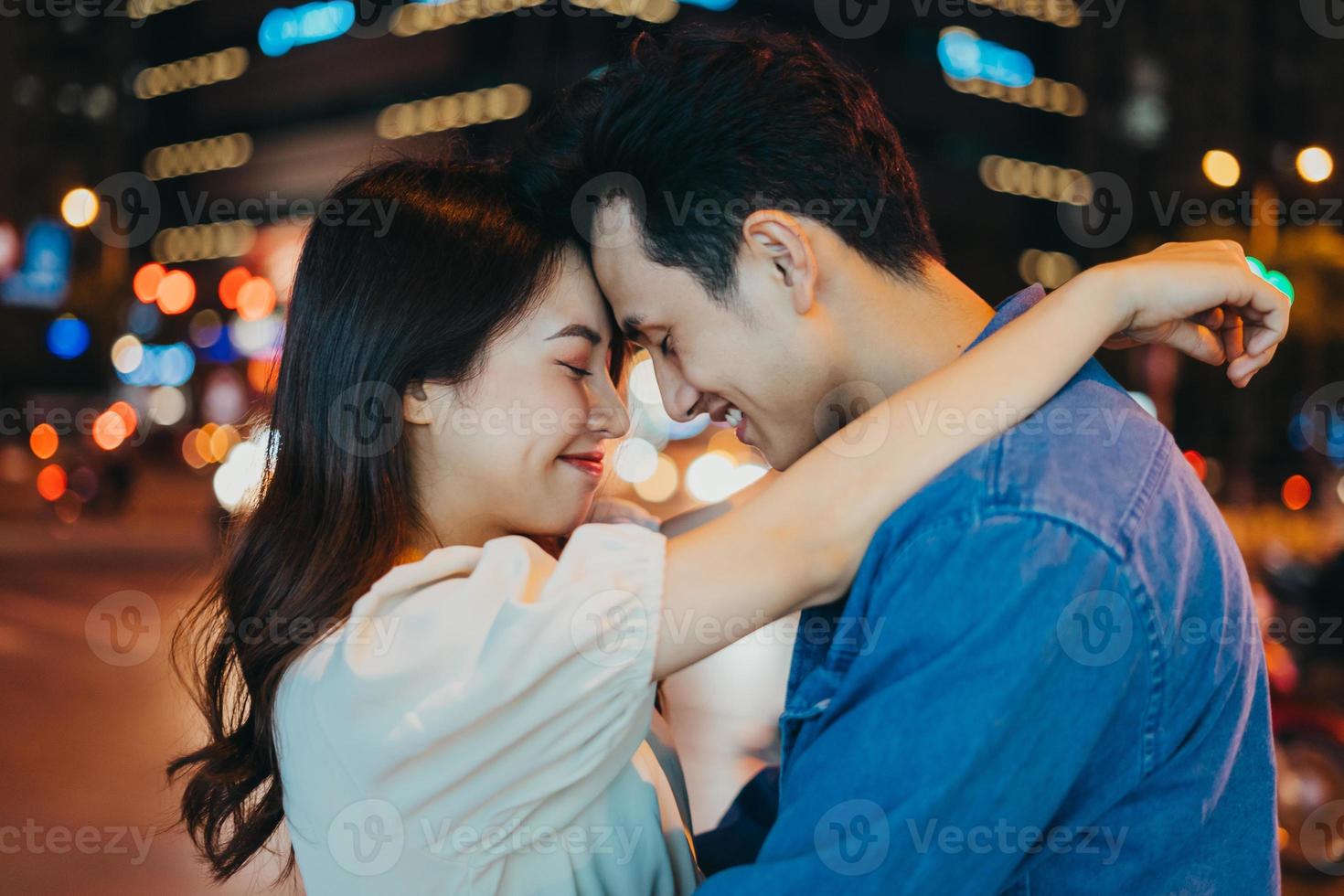 jeune couple asiatique embrassant ensemble dans la rue la nuit photo