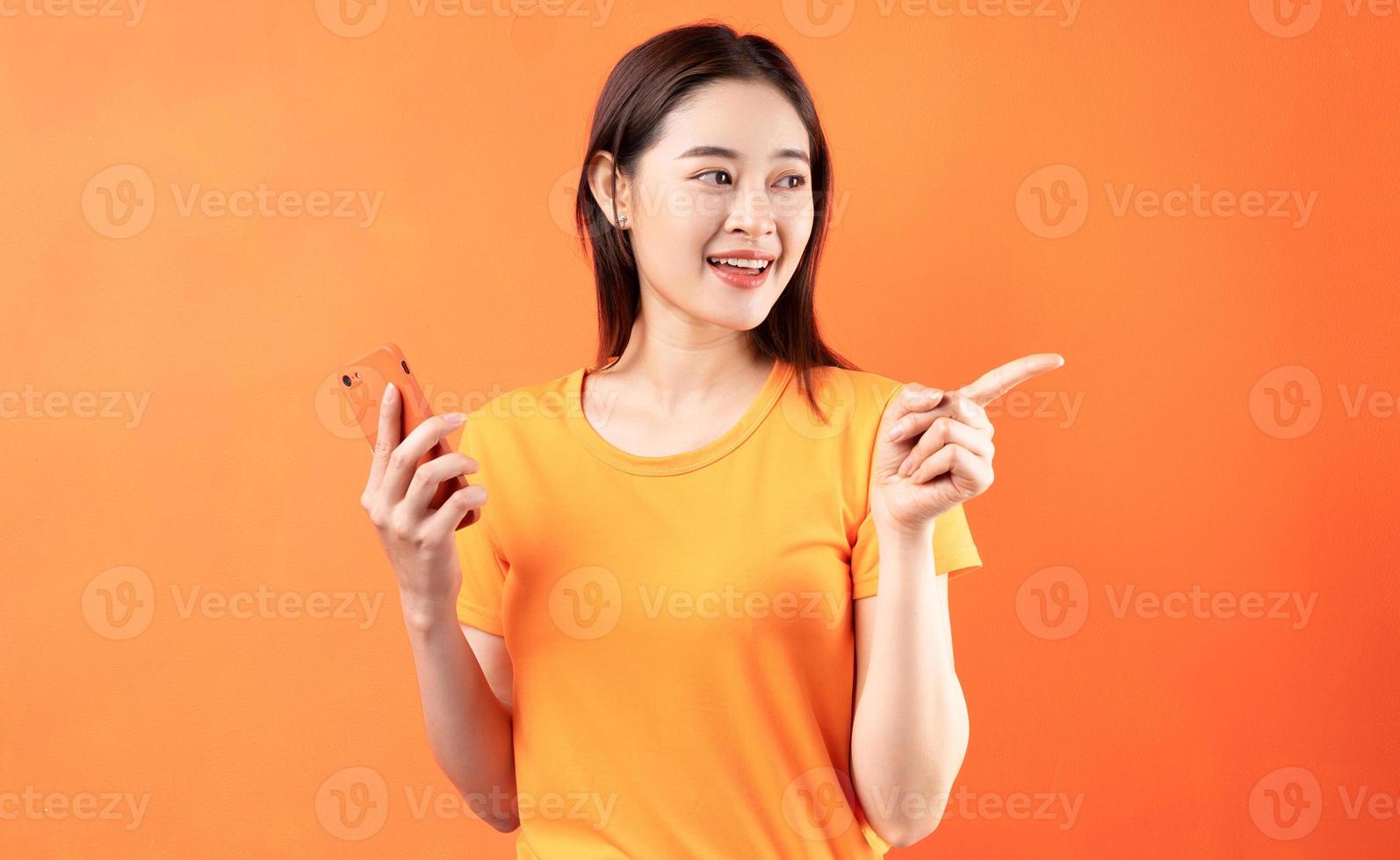 image de jeune femme asiatique tenant un smartphone sur fond orange photo