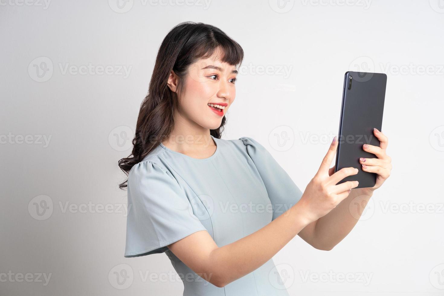 Jeune femme asiatique tenant une tablette sur fond blanc photo