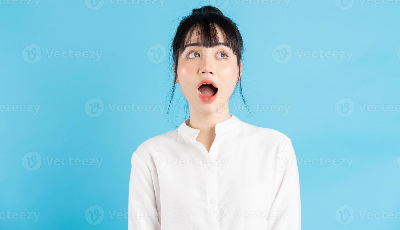 belle femme asiatique ouvrant grand la bouche sur fond bleu photo