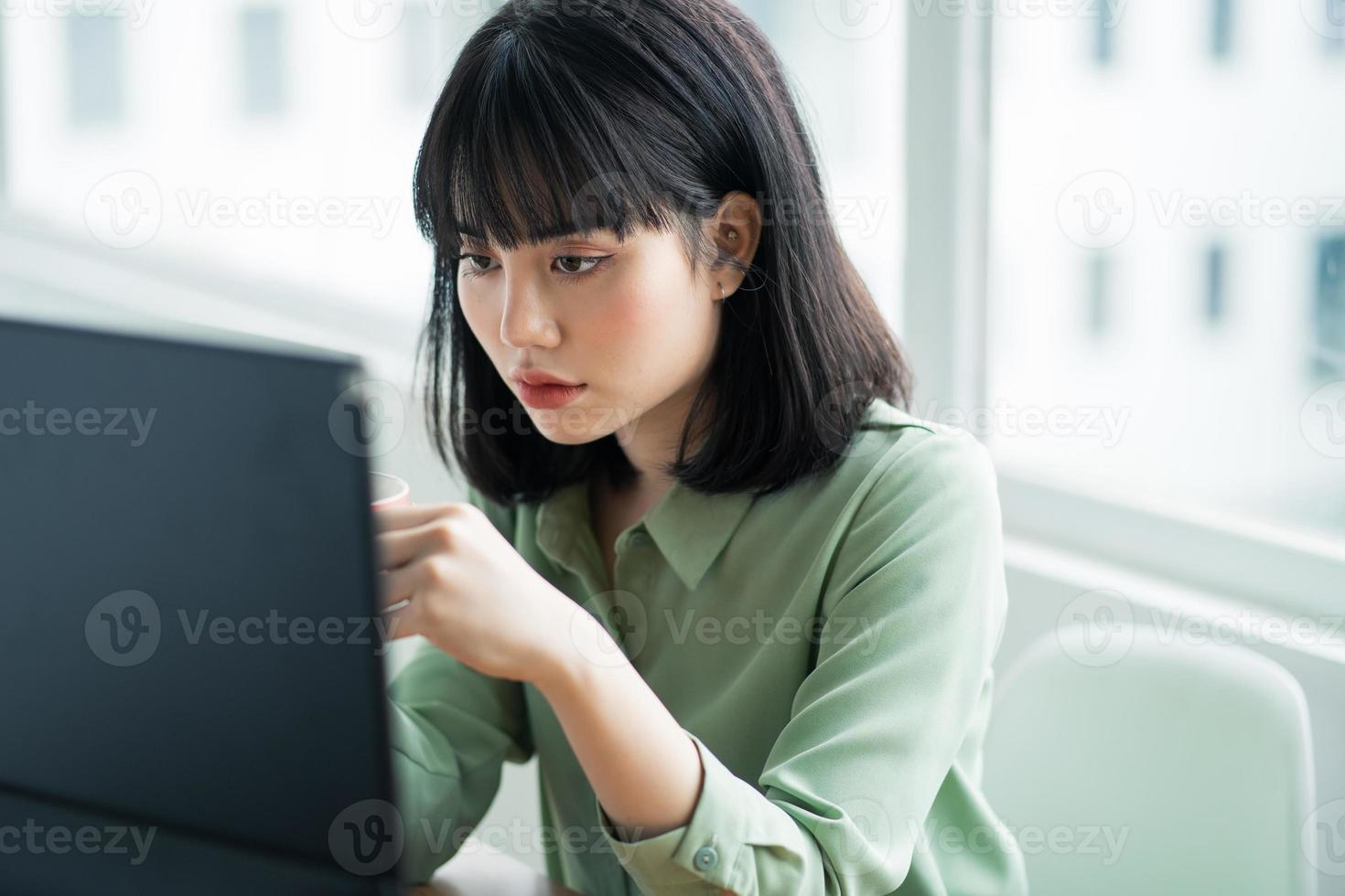 belle femme d'affaires asiatique assise et buvant du café à son bureau pendant la pause déjeuner photo